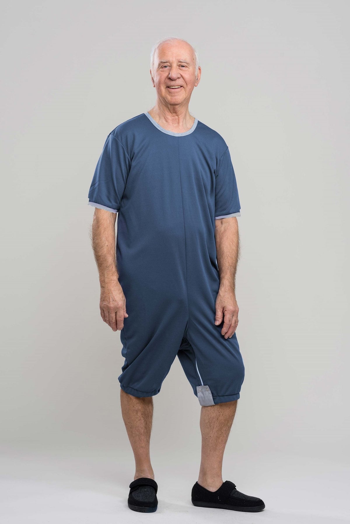 Adaptive short legs onesie designed for people suffering from dementia. A zipper on the back of the garment prevents the wearer from undressing. A large, zippered crotch opening facilitates diaper changes. Durable soft mesh knit dries quickly. Can be wo