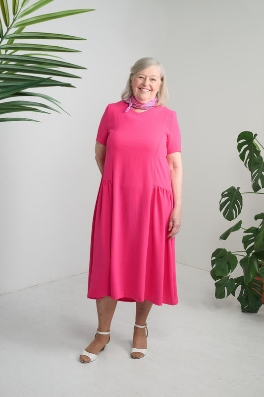 This adaptive dress boasts short sleeves and a light weight fabric, making it perfect for everyday wear. The large cut-out and lovely pleatings add a touch of elegance and the solid fuchsia color adds a pop of color to any wardrobe. Stay comfortable and s
